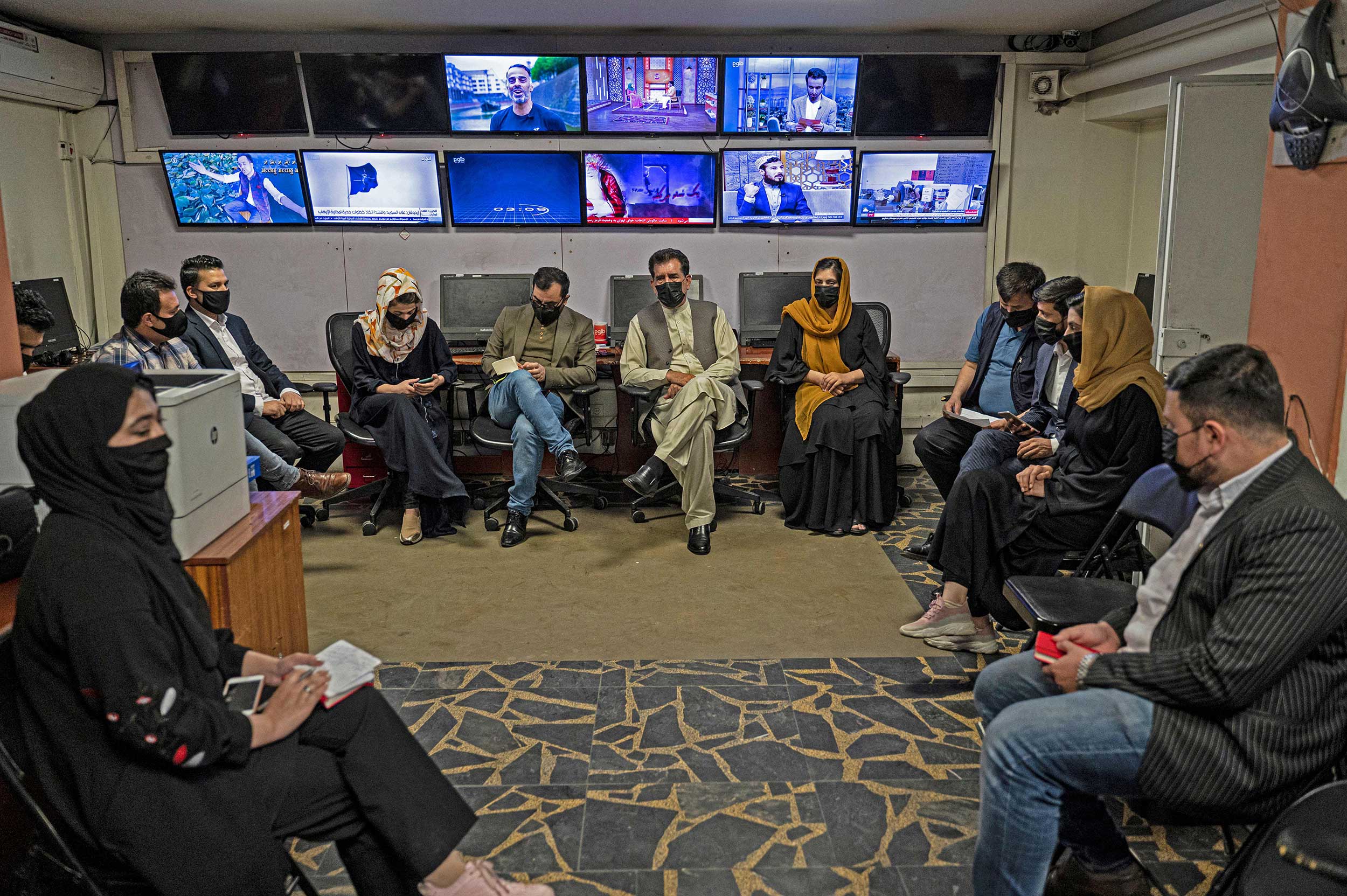 Reporters for Tolo News cover their faces as they attend an editorial meeting at Tolo TV station in Kabul on May 22, 2022. © WAKIL KOHSAR/AFP via Getty Images