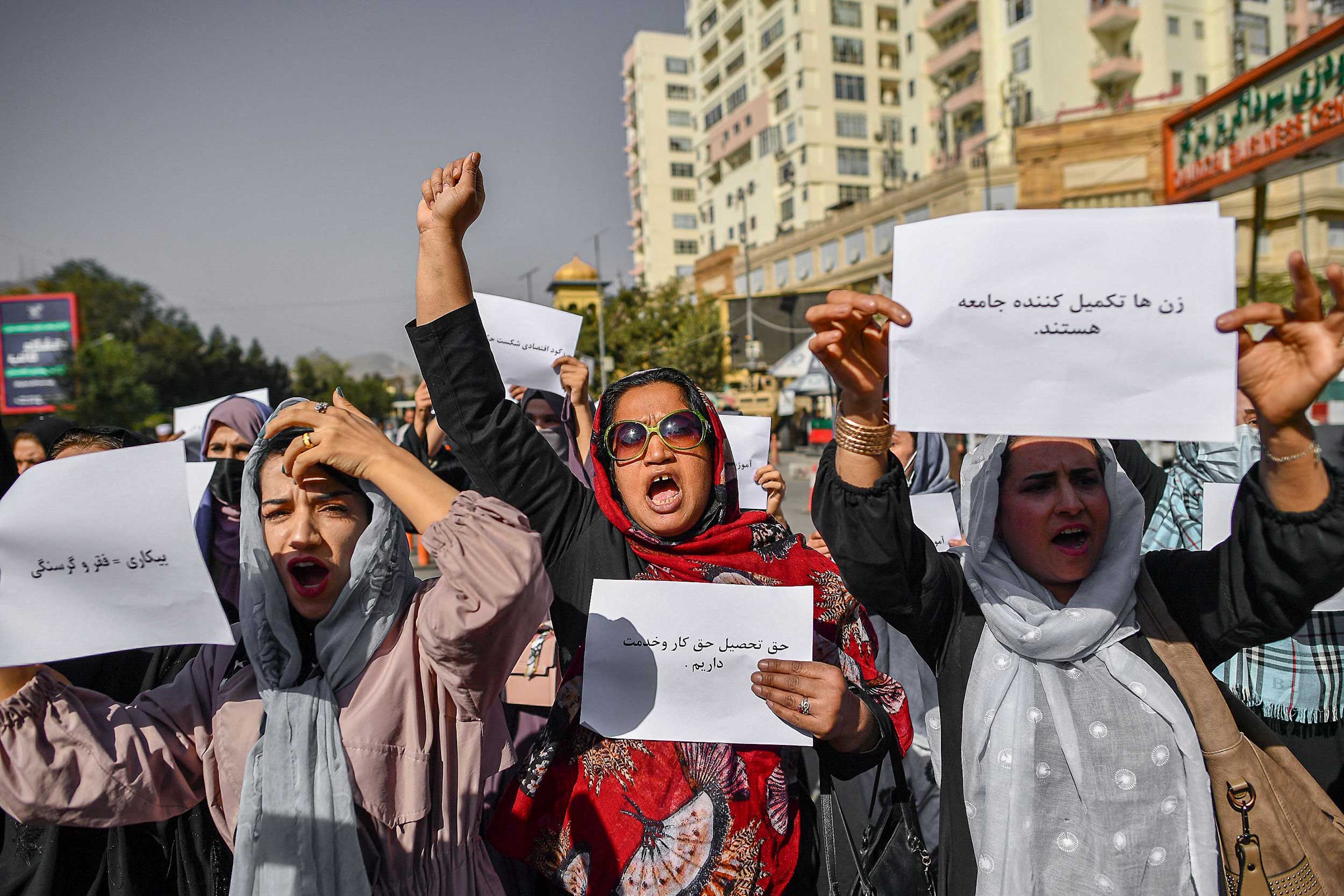 Afghan women chant slogans and hold placard during a women's rights protest in Kabul on October 21, 2021. The Taleban violently cracked down on media coverage of the protest in Kabul, beating several journalists. © BULENT KILIC/AFP via Getty Images