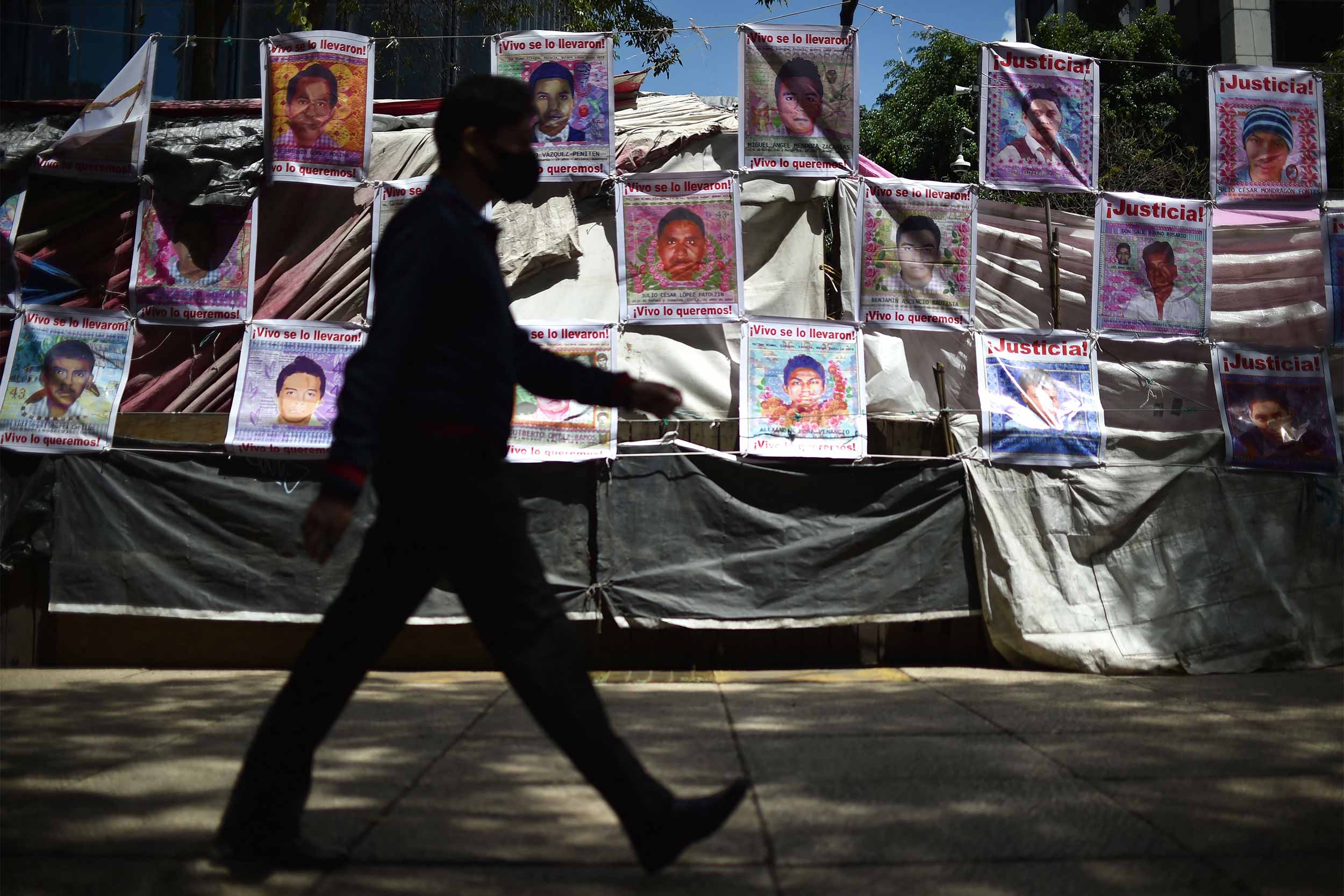 A man walks in front of the memorial site for the 43 missing students from the Ayotzinapa Rural Teachers' College in Mexico City, on August 23, 2022. © Rodrigo Arangua/AFP via Getty Images