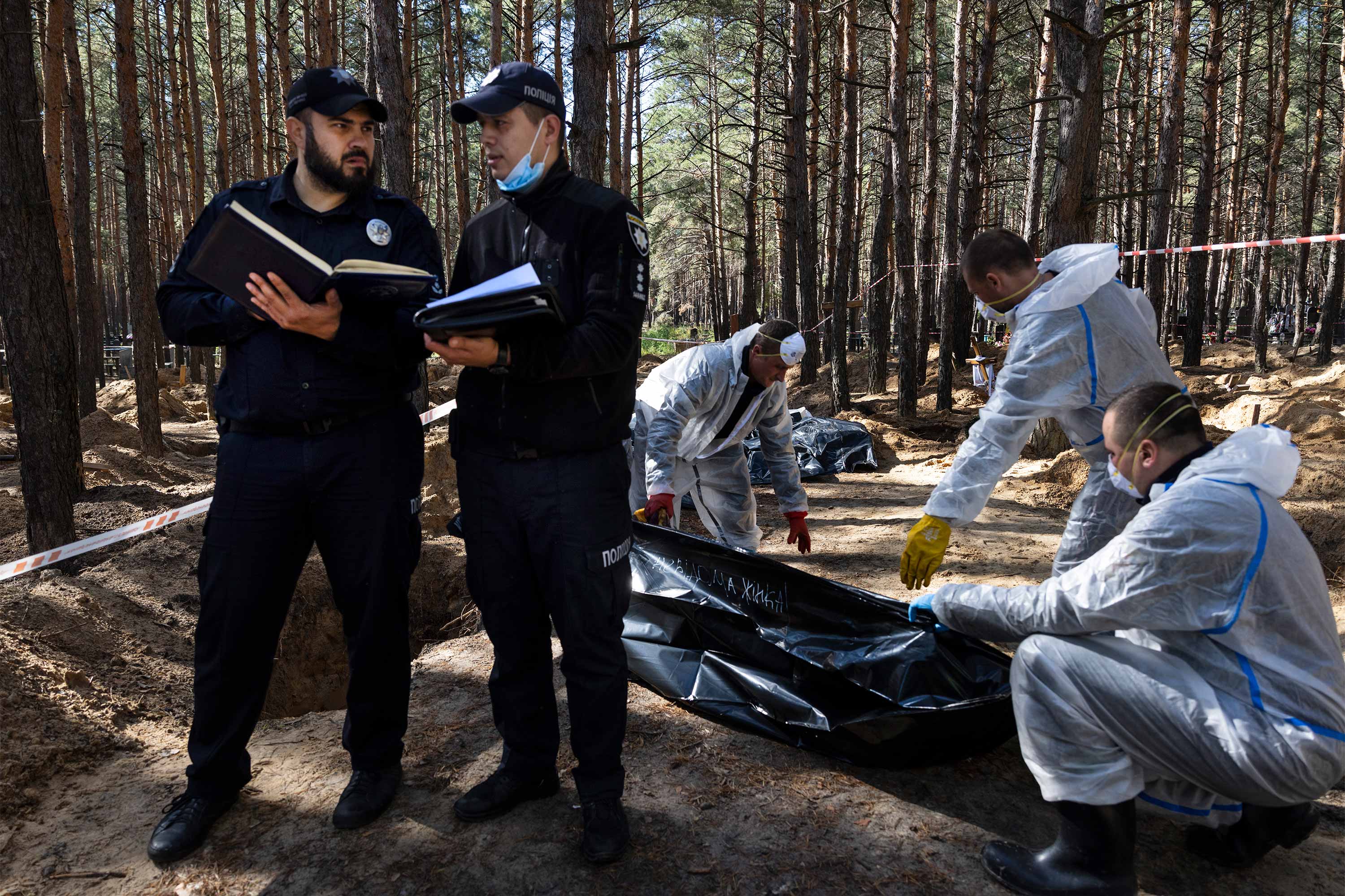 Rescue workers and forensic police exhume bodies from unidentified makeshift graves at the Pishanske cemetery on September 21, 2022 in Izium, Ukraine. The bodies will be examined by forensic officials for possible war crimes. Izium was liberated from Russian occupation after six months. Approximately 440 bodies are buried at the cemetery, so far over 338 bodies have been exhumed, taken to the morgue in Kharkiv. © Paula Bronstein/Getty Images
