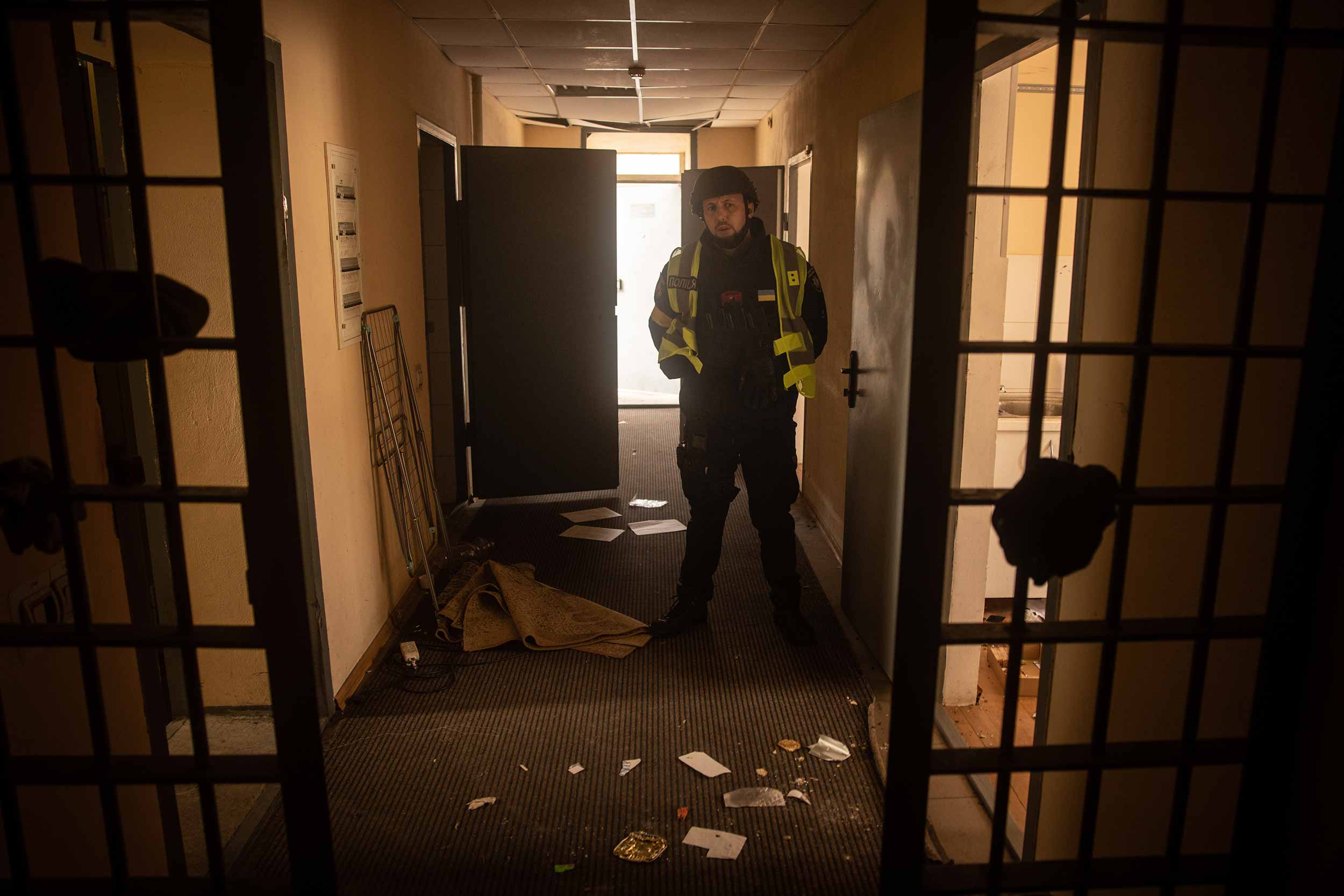 A Ukrainian police officer stands guard in the hallway of a preliminary detention centre which is believed to have been used by Russian forces to jail and torture civilians on November 16, 2022 in Kherson, Ukraine. © Chris McGrath/Getty Images