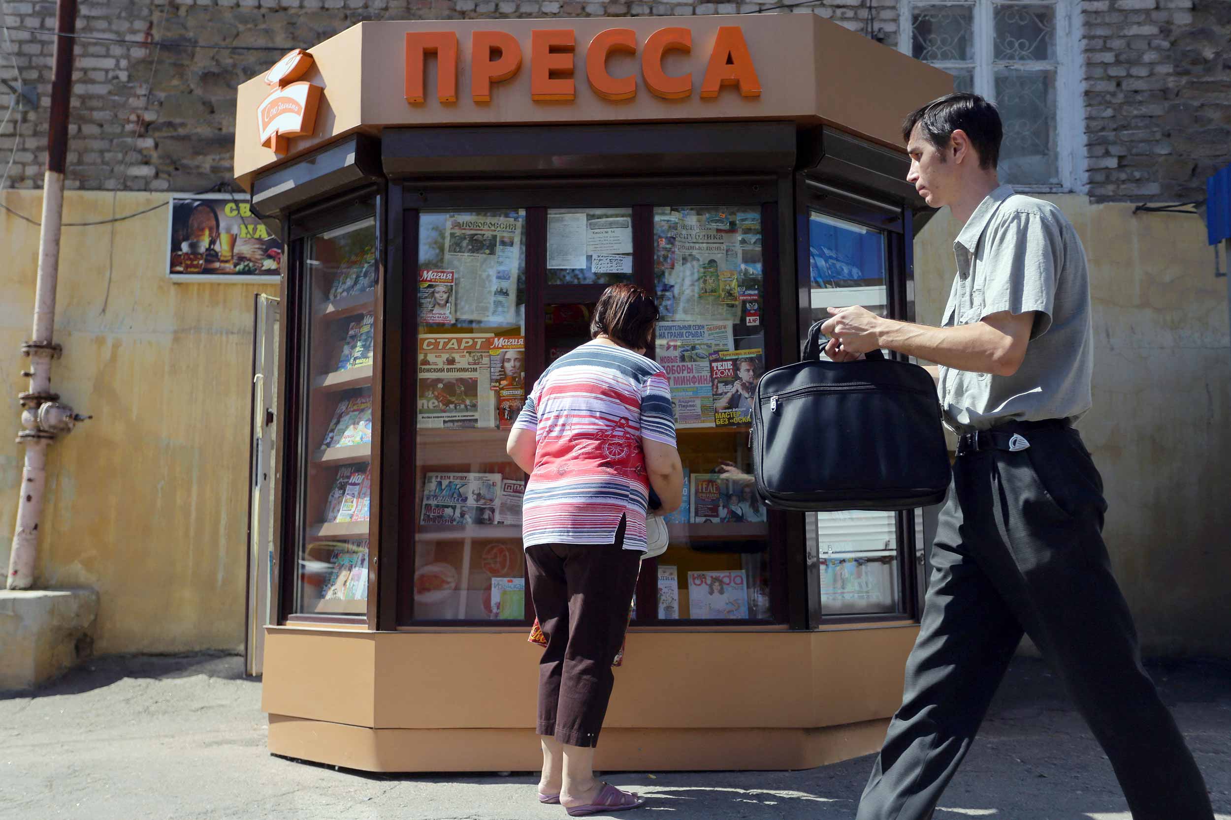 A man walks past a woman buying a magazine from a newspaper stand in Donetsk. Yana Agafonova, a media official in the pro-Russian rebel government in eastern Ukraine, says critical publications are not welcome in the separatist region, which is locked in a vicious propaganda war with Kiev. © OLEKSII FILIPPOV/AFP via Getty Images