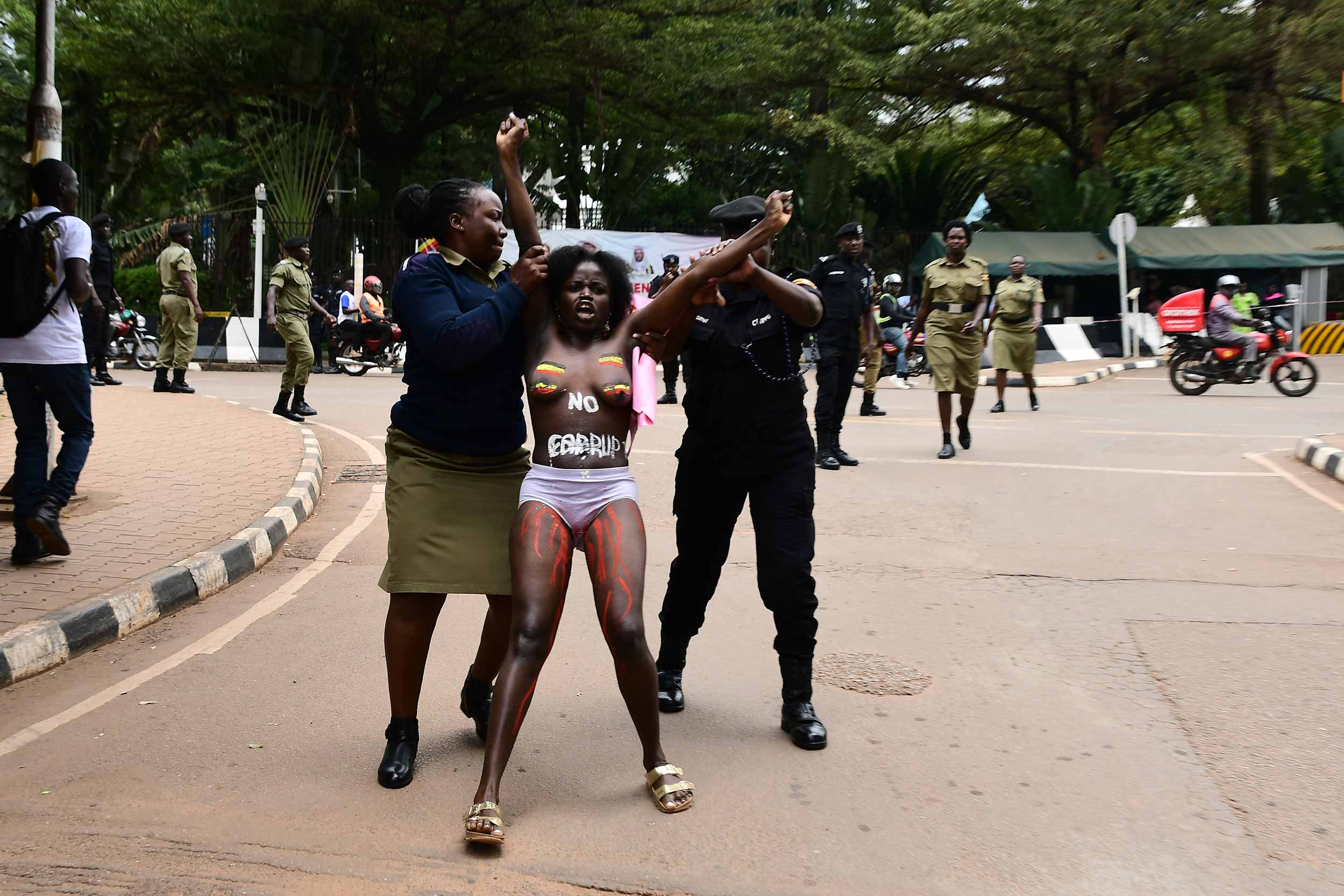 Two female police officers arrest Aloikin Praise Opoloje on September 2 2o24. It was the second time she was attempting to march to parliament in a protest against corruption. © Haggai Matsiko/IWPR/Agora