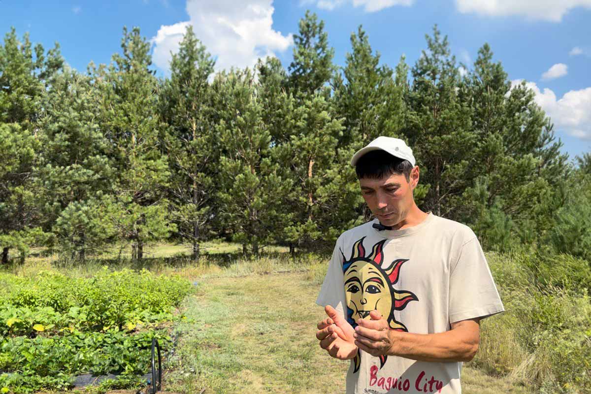 Timur Makarov, 47, in front of the hedgerow surrounding his plot. Makarov met his wife, Saida, in Vedrukh. Like all the other children living in the settlement, their son and daughter attend school in a nearby village. © Talgat Umarov