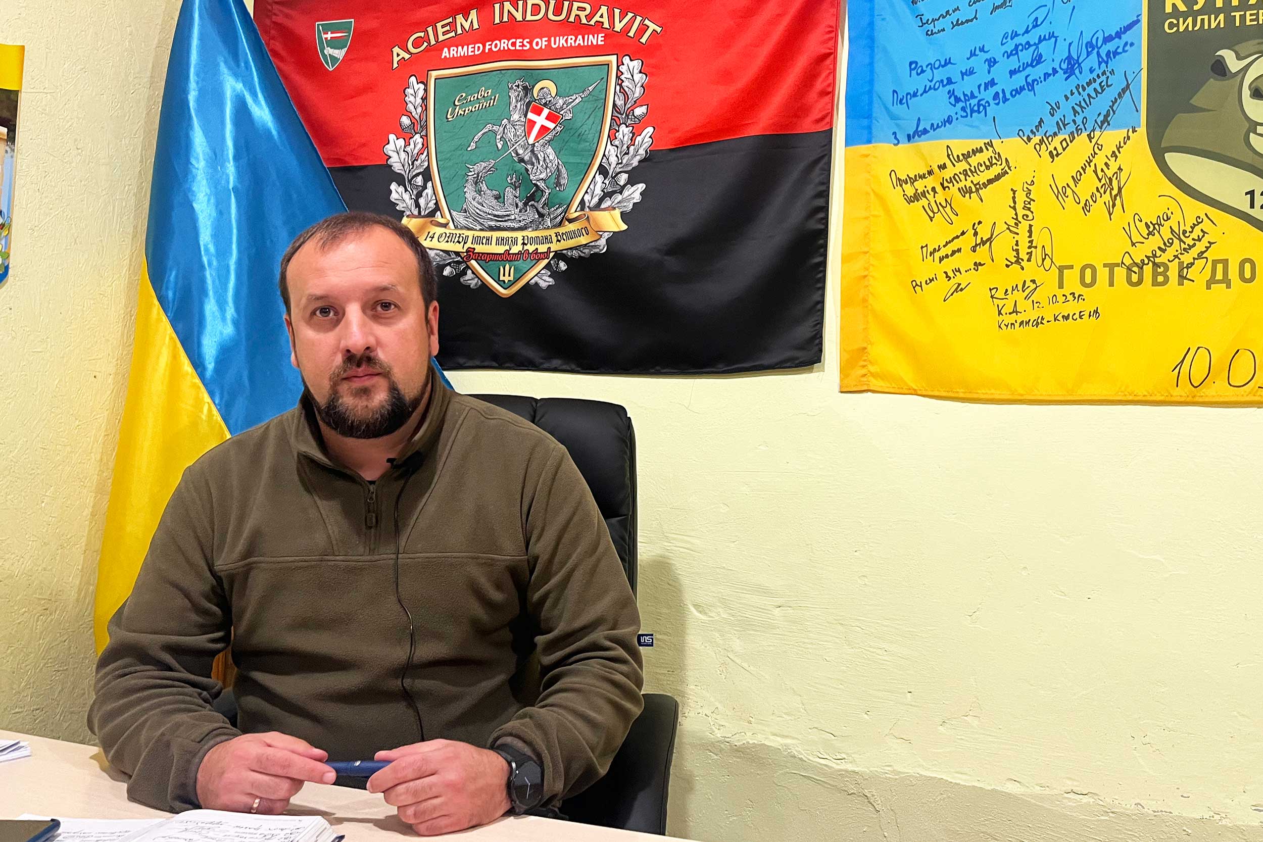 Andrii Besedyn, head of the town’s military administration, with flags commemorating the liberation of Kupiansk. Russian attacks are increasing, and the population is evacuating. © IWPR