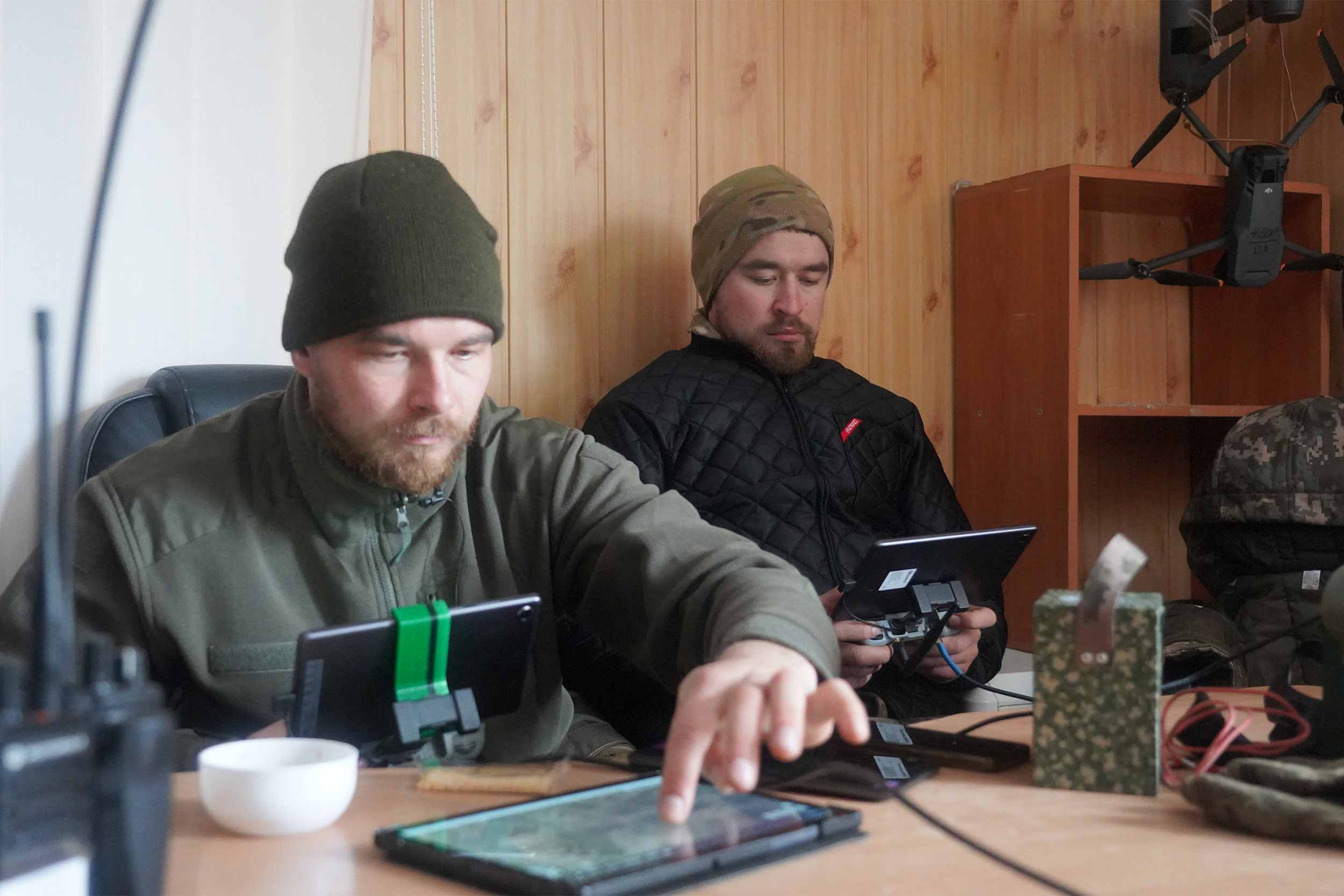 Anton (left) and Sasha (right), aka the Peaky Blinders, work on their devices, which guide artillery-loaded drones. The Kharkiv-born brothers used to work in construction and farming before joining the army. © Kolyan Pastyko