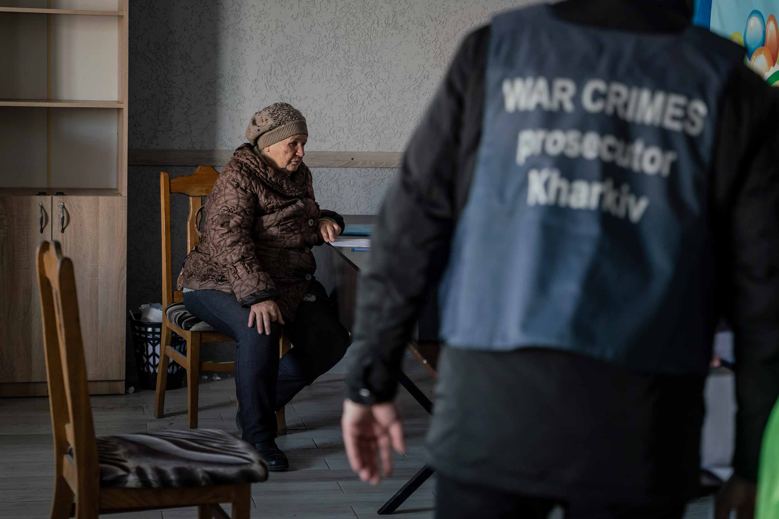A woman sits with a prosecutor in Izyum’s makeshift police station in a former shopping centre. Residents who are trying to locate the bodies of their beloved queue to give testimonies and provide DNA samples. © Danil Pavlov