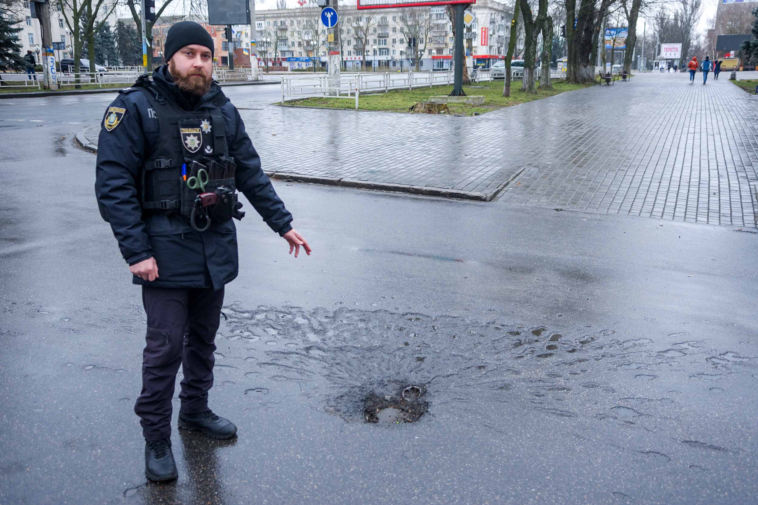 A policeman in Kherson shows the location where the first shell hit the Kherson market, December 24. In total, 11 people died, with more than 70 wounded. © M. Shtekel