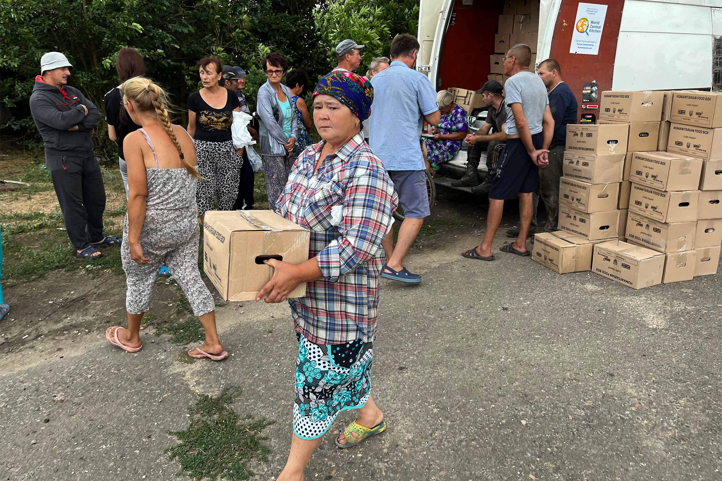 Oksana receives an aid box in Little Schevkenko, Mykolaiv oblast. Her son has been killed and her house damaged, yet she stays in her village. © Anthony Borden